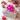 Gift box with a large pink bow on a wooden surface with flowers and another gift box.
