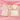 Baby gift set with polka dot outfit, pink heart, and card on pink fabric