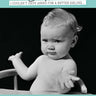 Black and white photo of a baby in a high chair with humorous birthday message on a teal background