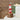 A red and white lighthouse wooden ornament with a ladder, displayed on a wooden block.