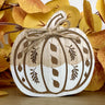 Wooden pumpkin decoration with twine on a background of autumn leaves