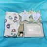 Baby gift set with onesie, cards, and toys on a blue background