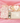 Baby gift set with 100% cotton sleepsuit, heart-shaped plaque, and other items on a pink background